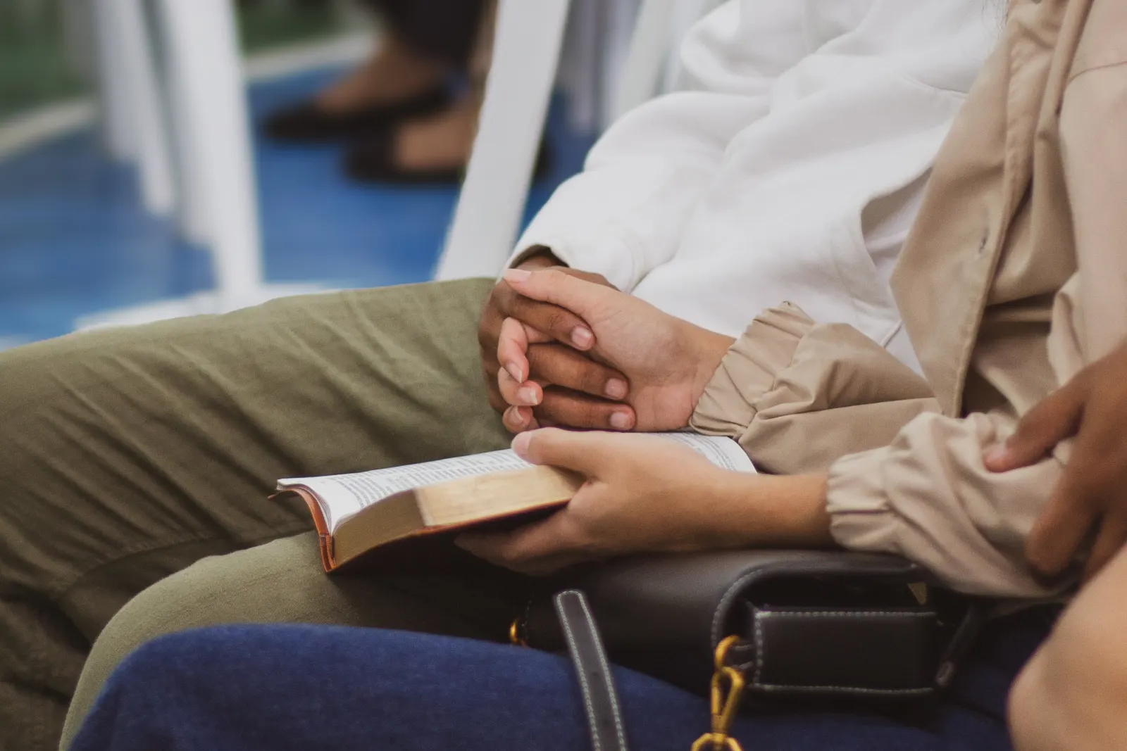 Mãos entrelaçadas sobre uma Bíblia aberta durante o culto.